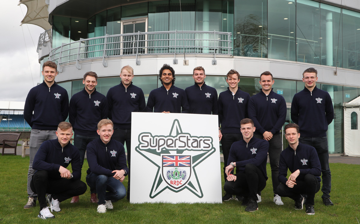 superstars1 A group of BRDC SuperStars pose outside the BRDC Cubhouse at Silverstone behind a large print of the programme logo